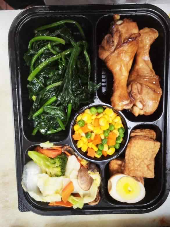 Braised drumsticks and fried tofu Bento box with sauteed greens, braised chicken drumsticks, corn and carrot medley, fried tofu with boiled egg, and mixed vegetables