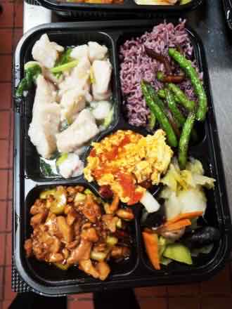 Purple rice box, close up Close-up of a five-compartment bento box holding poached fish fillet with greens, purple rice, green beans, tomato scrambled egg, diced chicken with peanuts, and cabbage with wood ear and carrot