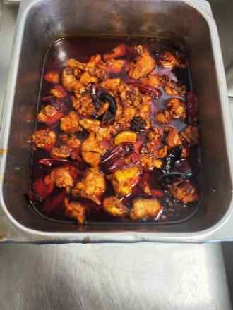 Braised chicken with dried chilies Steam-table pan of bone-in chicken pieces braised in a dark red chili oil sauce with whole dried red chilies