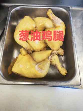 Stainless steel tray holding four whole scallion oil chicken leg quarters with glossy yellow skin