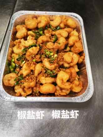 Catering tray of golden battered fried shrimp tossed with sliced green jalapeno, scallion and garlic seasoning