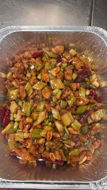 Catering tray of Kung Pao chicken with diced celery, peanuts, whole dried red chilies and scallion